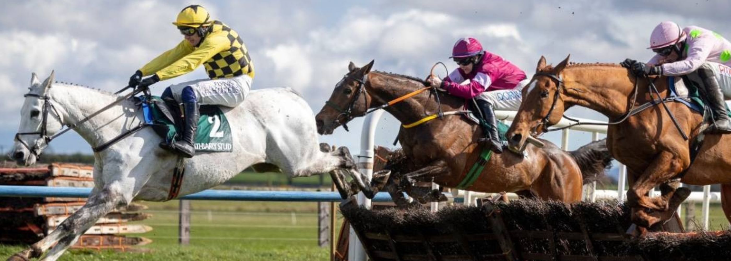 Horses and jockeys racing on a track with a cloudy sky at Fairyhouse Race Course.
